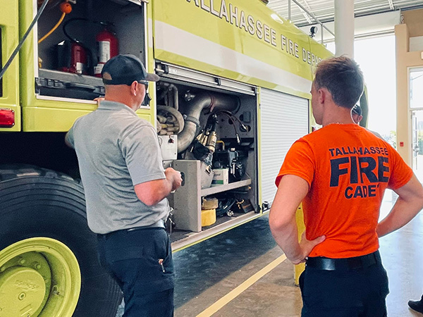 Back of a cadet watching an actual TFD employee show off his equipment